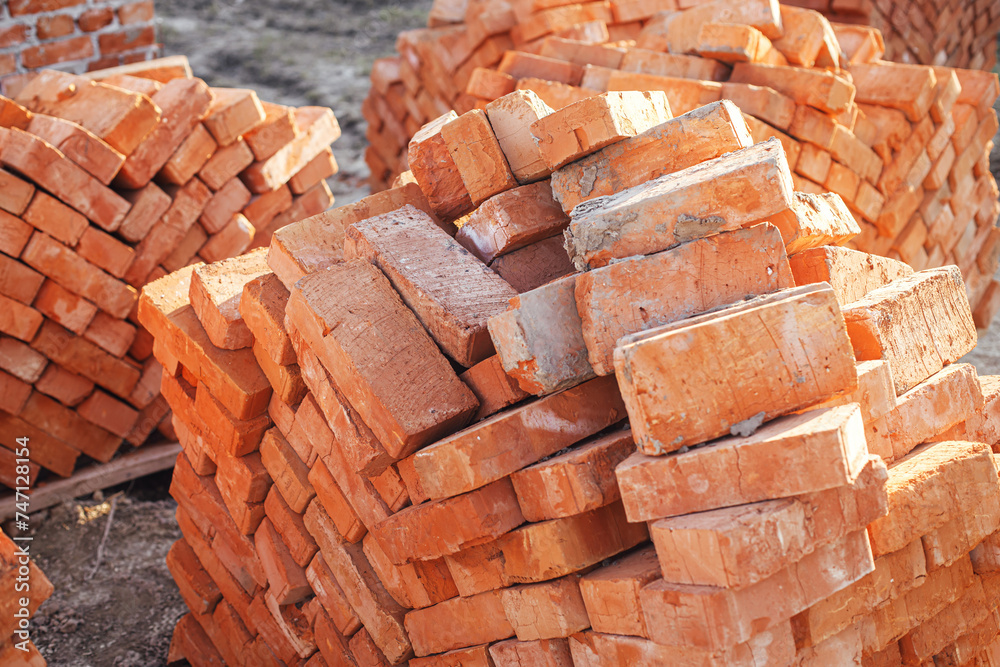 Stack of red bricks, process of house building. Bricks for laying on concrete foundation. Building materials at construction site Stack of red bricks, process of house building. Bricks for laying on concrete foundation. Building materials at construction site
