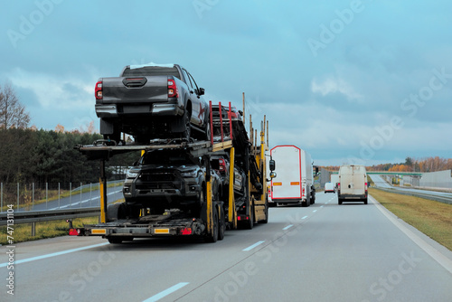Car carrier trailer truck with brand new off-road vehicles for sale. New car delivery. Car transporter trailer loaded with many new cars for the customers. Two-level modular hydraulic semi-trailer 
