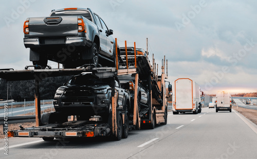 Car carrier trailer truck with brand new off-road vehicles for sale. New car delivery. Car transporter trailer loaded with many new cars for the customers. Two-level modular hydraulic semi-trailer