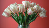Bouquet of fresh white tulips in a glass vase on a blurred red background.