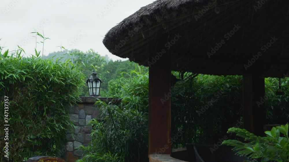 Explore owning slice of paradise with this tropical backyard grill house featuring thatched roof, glistening with rain in lush jungles. Ideal for those seeking serene escape in nature's embrace