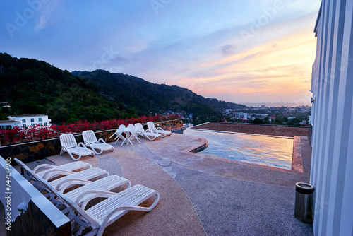 Swimming pool in sunset time with beatiful sea and city view.