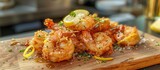 A wooden cutting board is displayed with sizzling fried shrimp, topped with lemon zest, creating a delectable and enticing culinary arrangement.