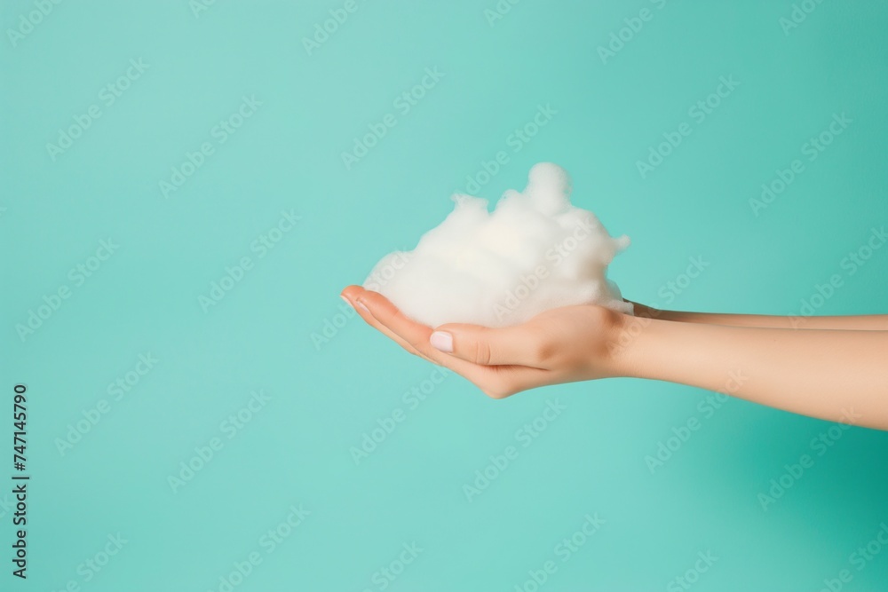Womans hands cradles a mound of fluffy white soap foam against a turquoise background Womans hands cradles a mound of fluffy white soap foam against a turquoise background