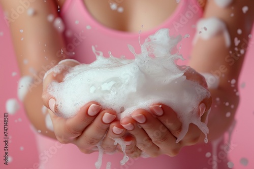 Hands cupping sudsy foam against a pink backdrop, highlighting hygiene with a playful touch