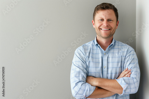 Confident Young Businessman in Casual Attire Leaning Against a Neutral Background with Ample Copy Space