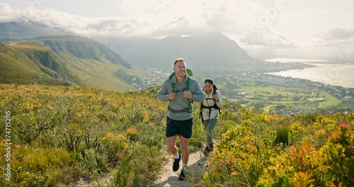 Couple of friends walking, hiking on mountain and travel for fitness, adventure or journey in nature for wellness. Young people trekking with backpack on a path or green hill for cardio and health photo