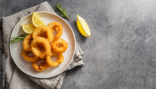 fried squid rings, squid dish. top view of fried squid rings with lemons on white plate, copy space, seafood