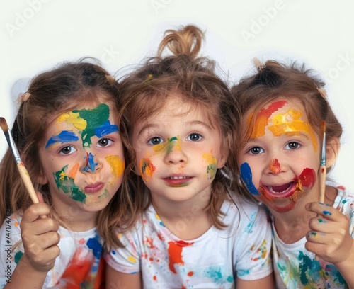 Three little girls with paint on their faces smiling and playing happily together at a colorful art party, world art day photography