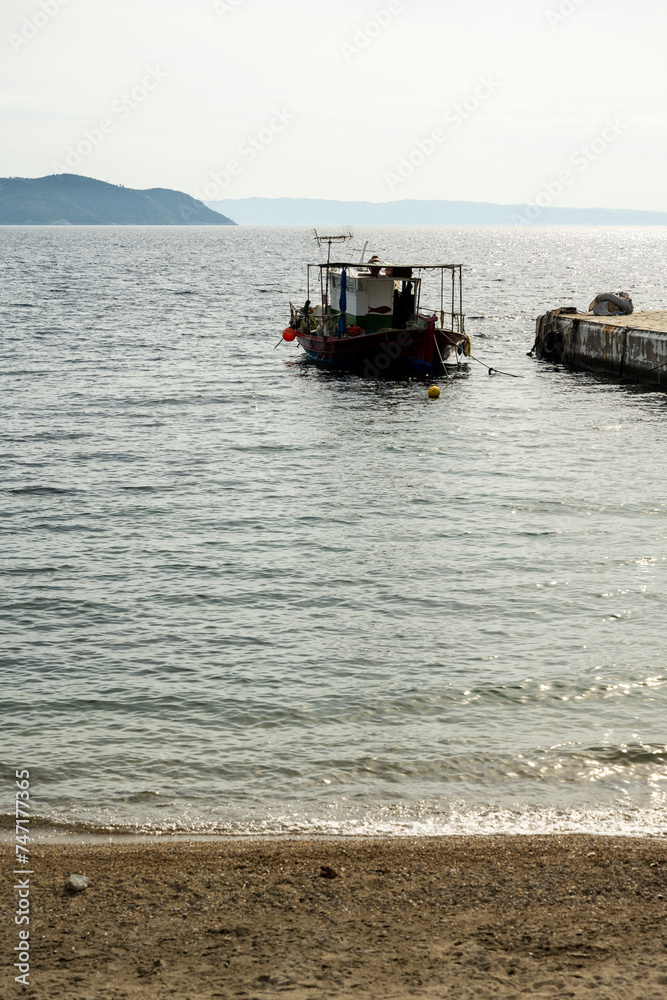 A small fishing boat is anchored at the dock. Sithonia, Greece, Halkidiki. Paradisos Beach in Neos Marmaras.
