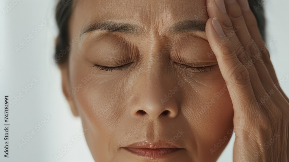 A woman with closed eyes pressing her hands against her temples conveying a sense of stress or discomfort. A woman with closed eyes pressing her hands against her temples conveying a sense of stress or discomfort.