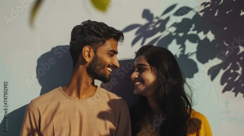 A joyful couple sharing a warm intimate moment their smiles reflecting happiness and connection set against a backdrop of a serene leafy wall.