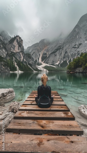 Serene young woman meditating on a wooden pier by the lake for mental well being and tranquility