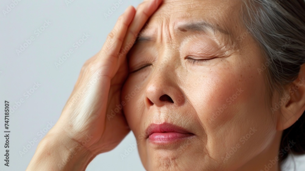 A woman with closed eyes pressing her hand against her forehead showing a sense of distress or deep thought. A woman with closed eyes pressing her hand against her forehead showing a sense of distress or deep thought.