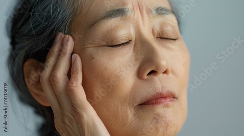 A close-up of an elderly person with closed eyes resting their head on their hand conveying a sense of contemplation or tiredness.