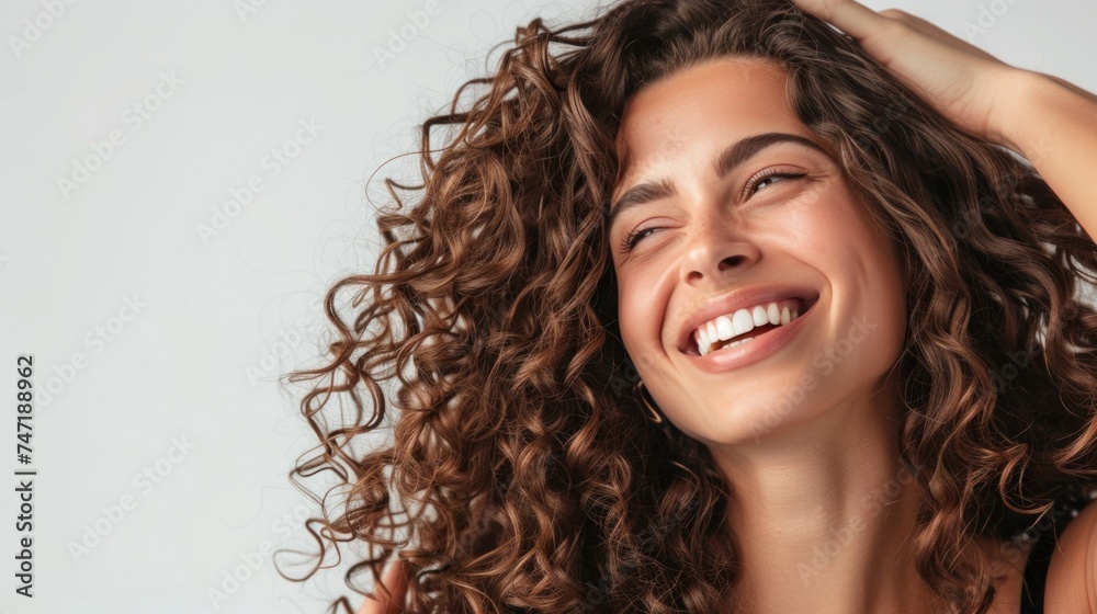 Smiling woman with curly hair looking up with hand on head. Smiling woman with curly hair looking up with hand on head.