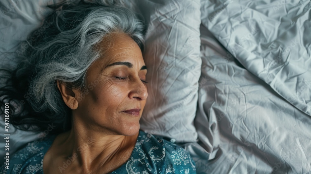 A serene portrait of a woman with gray hair peacefully sleeping on her side with her head resting on a pillow dressed in a blue patterned top. A serene portrait of a woman with gray hair peacefully sleeping on her side with her head resting on a pillow dressed in a blue patterned top.