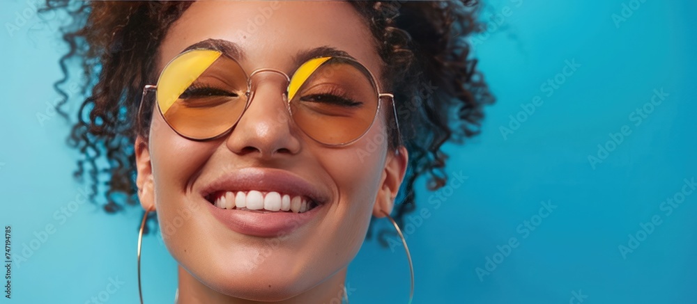 Portrait beautiful stylish young woman smiling wearing sunglasses on blue background. AI generated