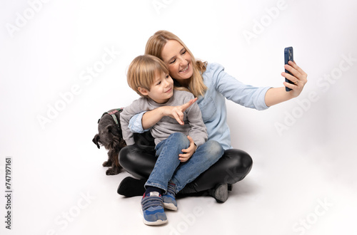 Smiling mother, child boy and dog taking a selfie isolated on white background