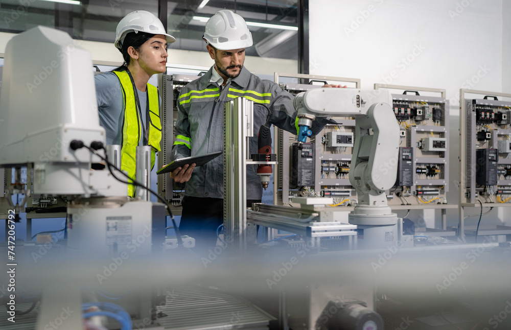 Hispanic engineer team working at electronic and robotics development engineering laboratory. Smart female technician learning futuristic robot innovation control from manager in automation research. Hispanic engineer team working at electronic and robotics development engineering laboratory. Smart female technician learning futuristic robot innovation control from manager in automation research.