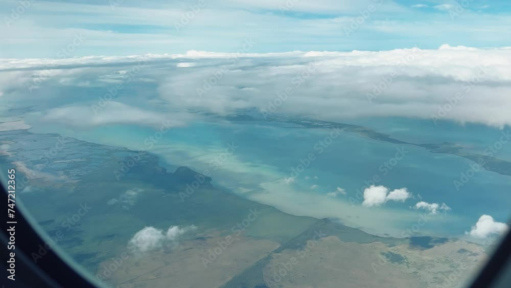 VARADERO, CUBA - DECEMBER 20, 2023: View from the porthole on the Atlantic coast of Cuba. View of the turquoise ocean water and islands with snow-white sand from the plane. White clouds over the water VARADERO, CUBA - DECEMBER 20, 2023: View from the porthole on the Atlantic coast of Cuba. View of the turquoise ocean water and islands with snow-white sand from the plane. White clouds over the water