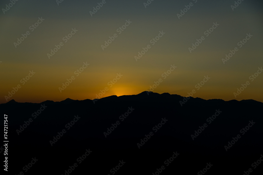 The sun sets among the mountains.