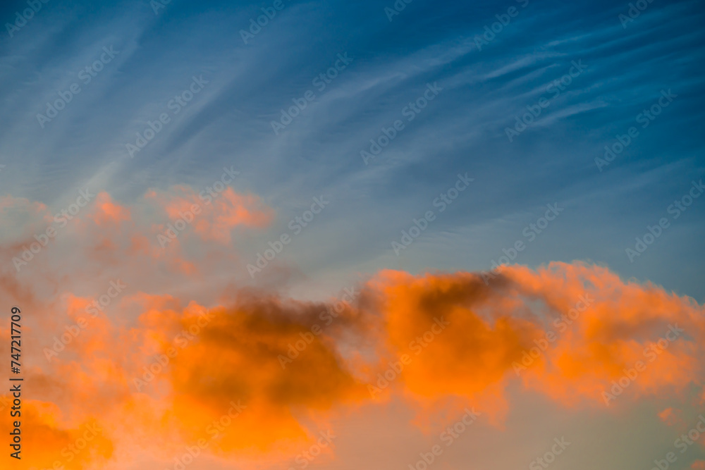Fototapeta premium Sinlit orange clouds in blue sky at sunset