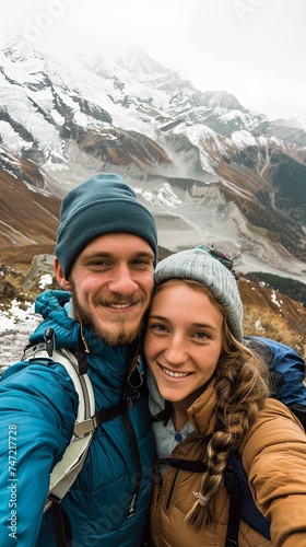 Vertical portrait of young happy man and woman on a mountain taking selfie
