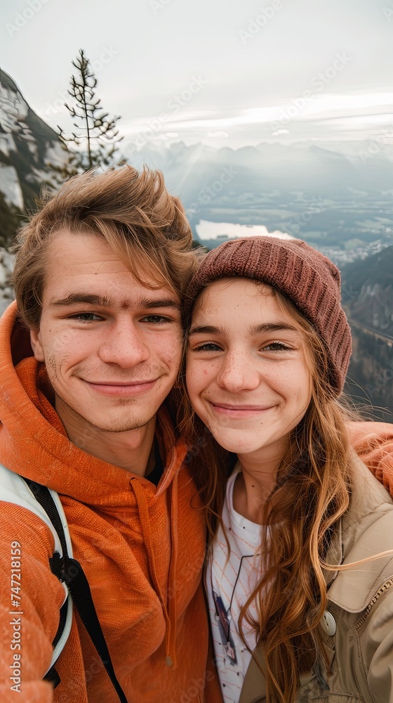 Vertical portrait of young happy man and woman on a mountain taking selfie Vertical portrait of young happy man and woman on a mountain taking selfie