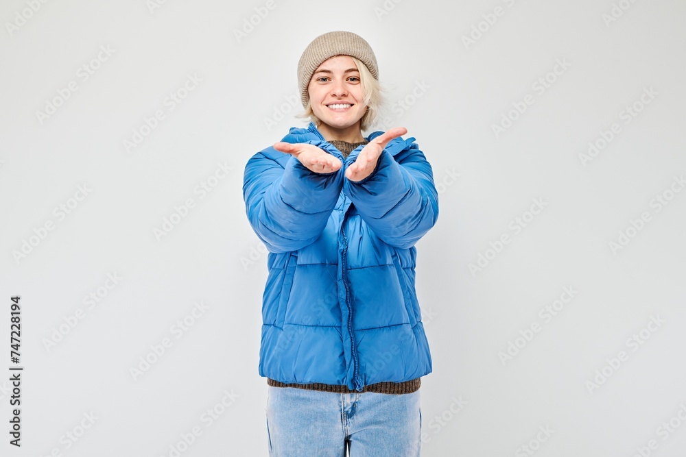 Smiling woman in winter clothes gesturing with hands on a gray background. Smiling woman in winter clothes gesturing with hands on a gray background.