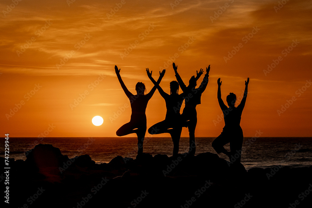 Silhouette women in Yoga Poses at Beach Sunset