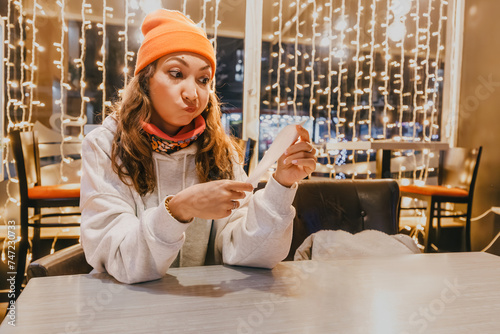 Startled woman scrutinizes the bill at the cafe, registering the crisis of emotion as she's shocked by the exorbitant price, realizing the hefty sum she must pay. photo
