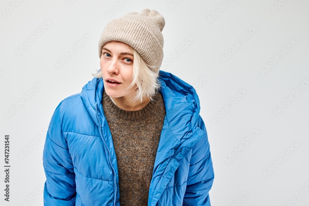 Woman in winter attire with beanie and blue puffer jacket looking away on a plain background. Woman in winter attire with beanie and blue puffer jacket looking away on a plain background.