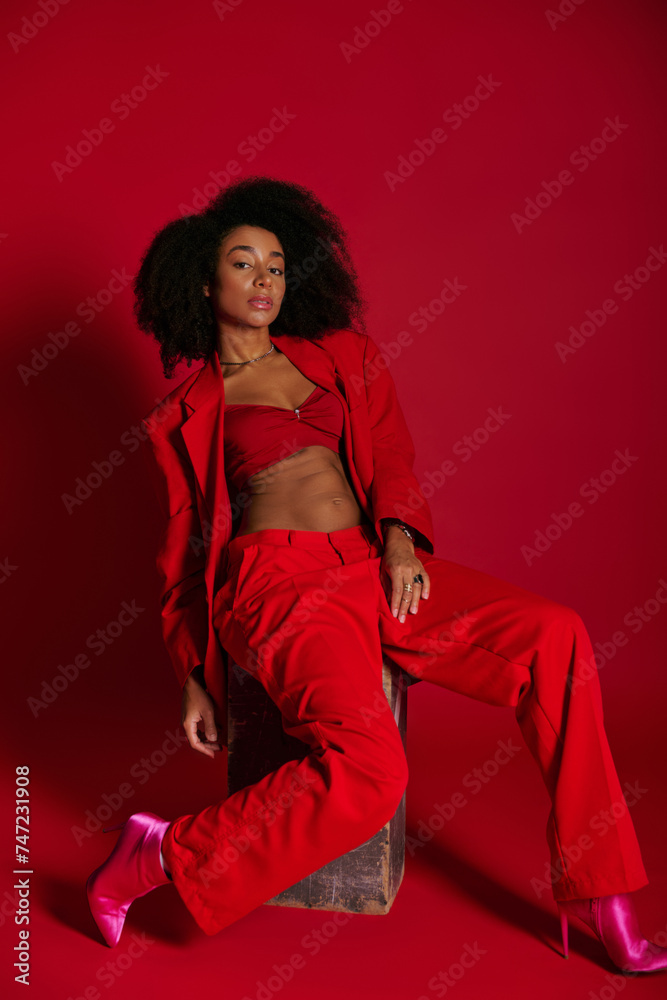 appealing sexy african american woman in red attire sitting and looking at camera, fashion concept appealing sexy african american woman in red attire sitting and looking at camera, fashion concept