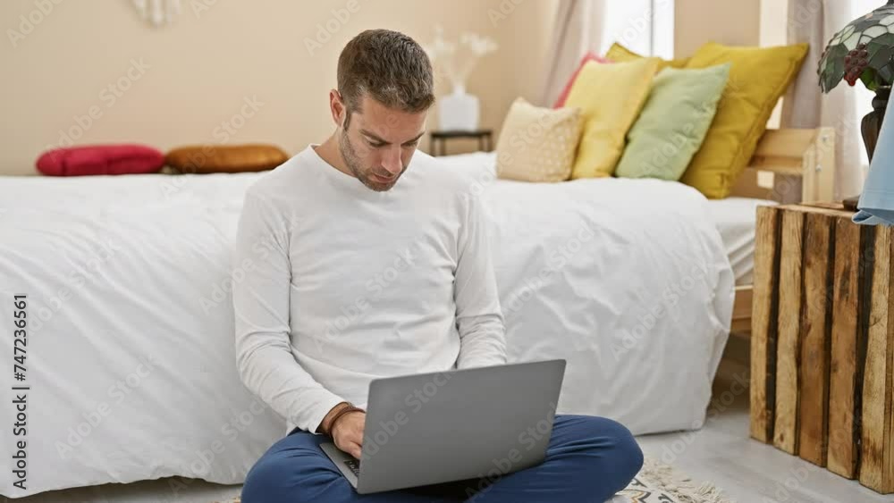 A focused man using a laptop in a cozy bedroom, embodying modern remote work. A focused man using a laptop in a cozy bedroom, embodying modern remote work.