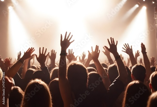 This party's on fire, Multiple people at a concert with their hands raised towards a brightly lit stage