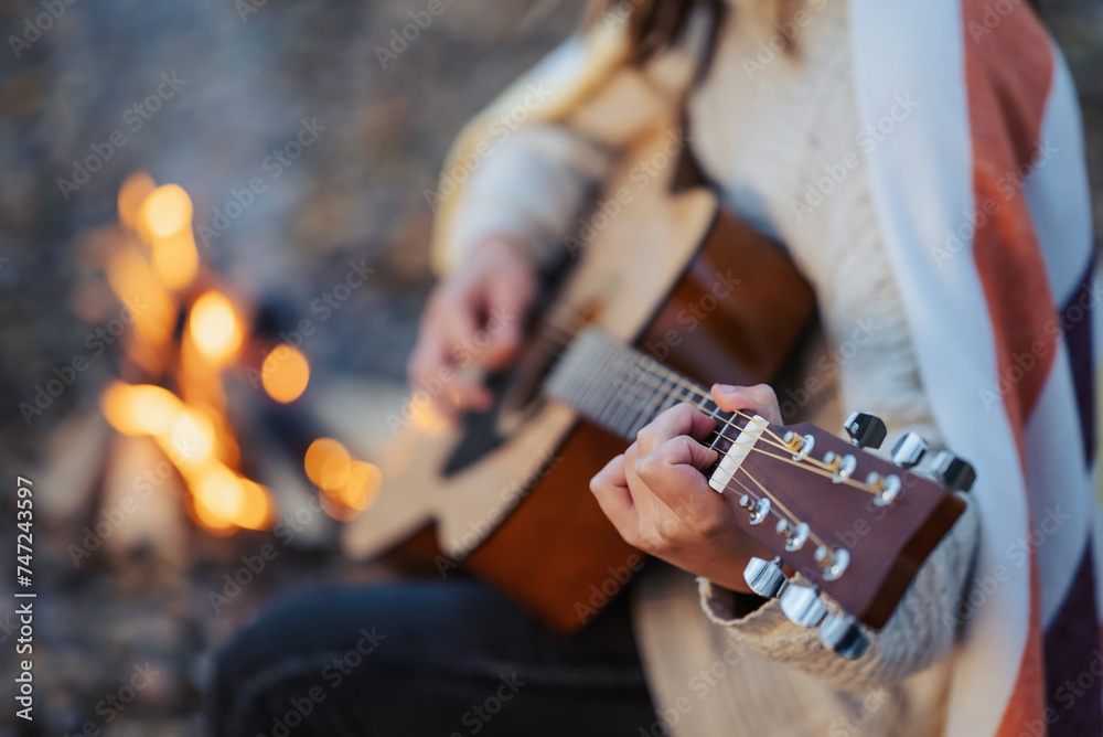 Close up of a girl playing the guitar near bonfire. Playing the guitar outdoors on nature, having good time with friends near the fire - obrazy, fototapety, plakaty 