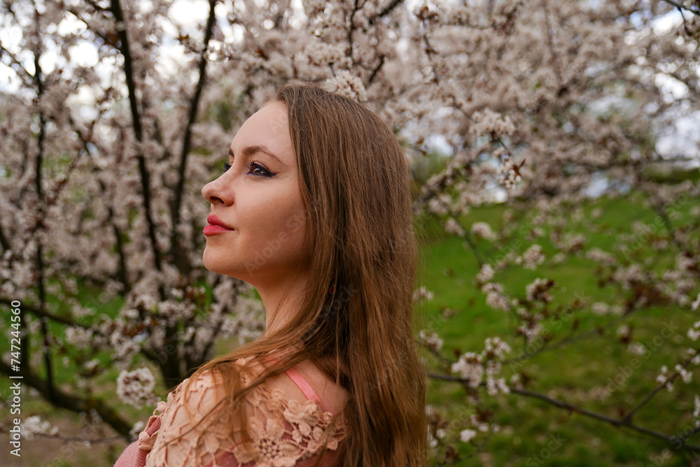 beautiful blond natural hair woman portrait in pink outfit is posing in botanical garden park near white blooming tree with flowers. Spring and purity, natural beauty. beautiful blond natural hair woman portrait in pink outfit is posing in botanical garden park near white blooming tree with flowers. Spring and purity, natural beauty.