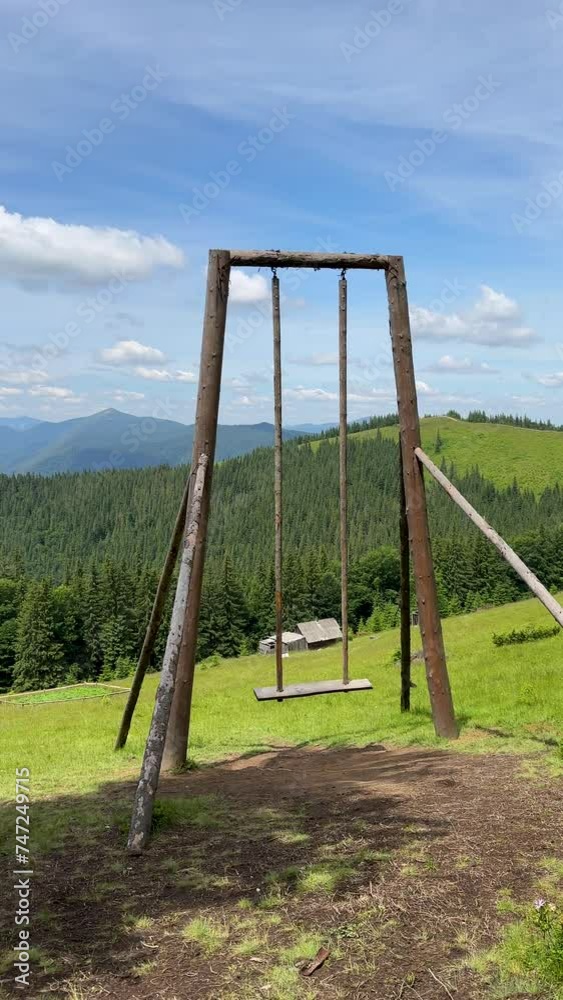 Large wooden swing with a picturesque view of the mountains on a sunny summer day. Recreation place for tourists in the mountains. Vertical video Large wooden swing with a picturesque view of the mountains on a sunny summer day. Recreation place for tourists in the mountains. Vertical video
