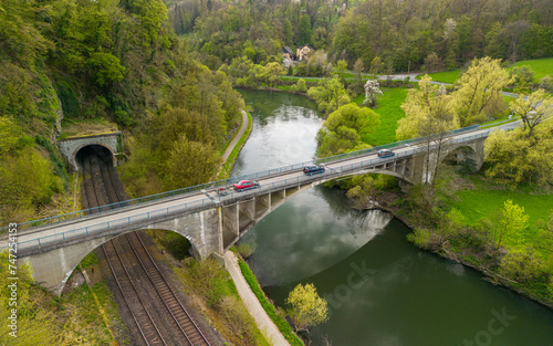 Cars driving on the bridge over the river and the train tracks in the German countryside 