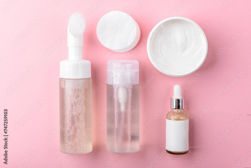 Facial cotton pads, foam, tonic, serum and cream on pink background. Facial skin care. Facial cotton pads, foam, tonic, serum and cream on pink background. Facial skin care.