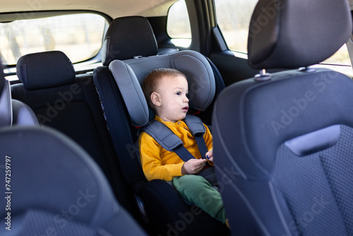 Boy sitting in safety car booster seat. Family and childhood journey concepts.