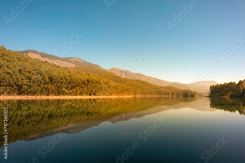 Beautiful, calm lake flanked by trees and mountains in Munnar, Kerala, India.
