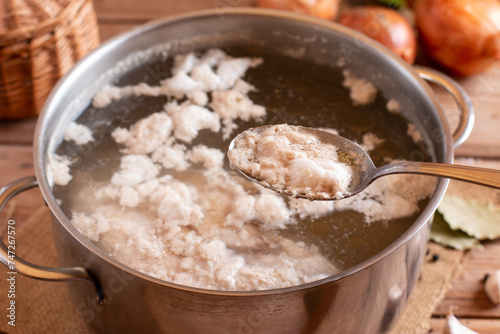 Foam from cooking chicken. Boiling water in a pan. Bone broth