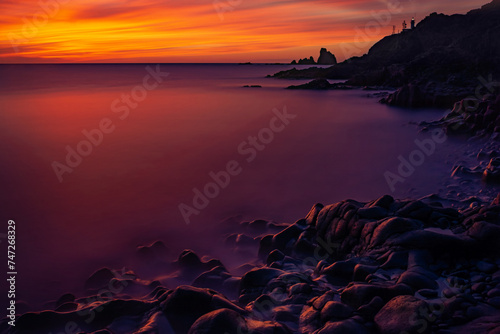 Beautiful views of the sunset over the sea  nature photo at sunset colourful and dramatic over the ocean  with last rays of light in the background. A lighthouse illuminates over the cliff.