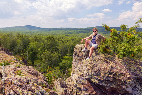 a young man rests on the rocks in the mountains of the Southern Urals on a summer sunny day