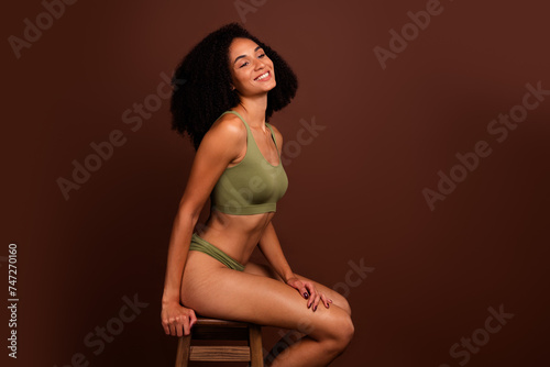 Profile side no filter photo of stunning woman ideal sporty skinny shape sit stool advertise underwear isolated on brown color background