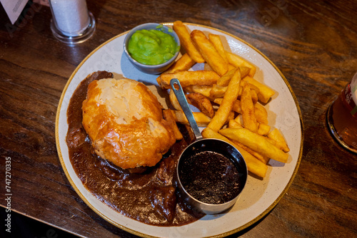 Edinburgh UK: 16th Feb 2023 Traditional steak and ale pie and a pint in a Scottish pub with chips, gravy and mushy peas