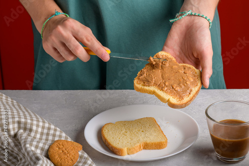 Close up of white bread toast with spreading peanut butter and knife, american breakfast