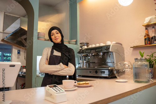 Portrait of young woman in hijab working in cafe